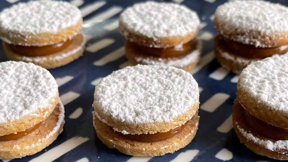 Cookies with caramel filling and powdered sugar on a blue and white patterned surface